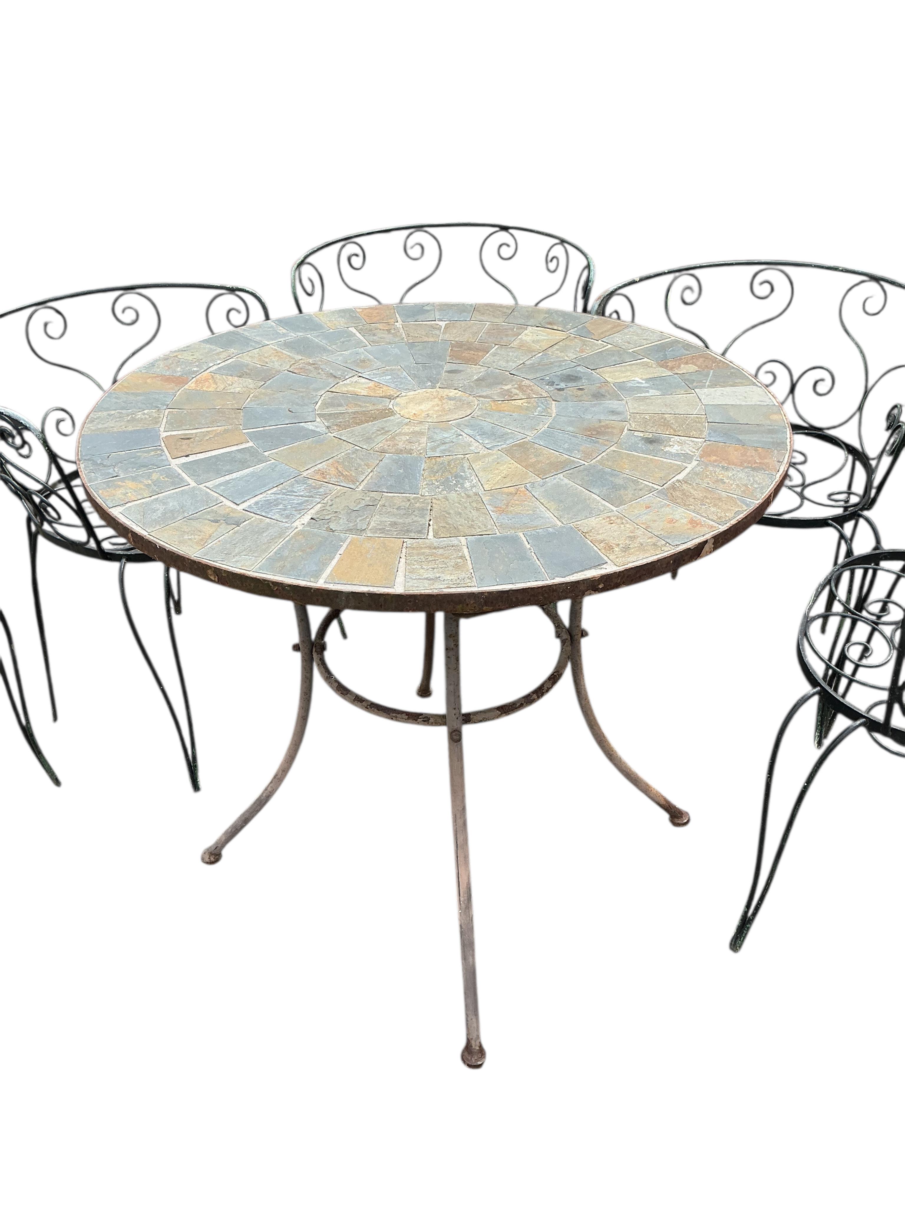 A circular stone mosaic topped garden table, diameter 80cm, height 72cm and six wrought iron garden chairs